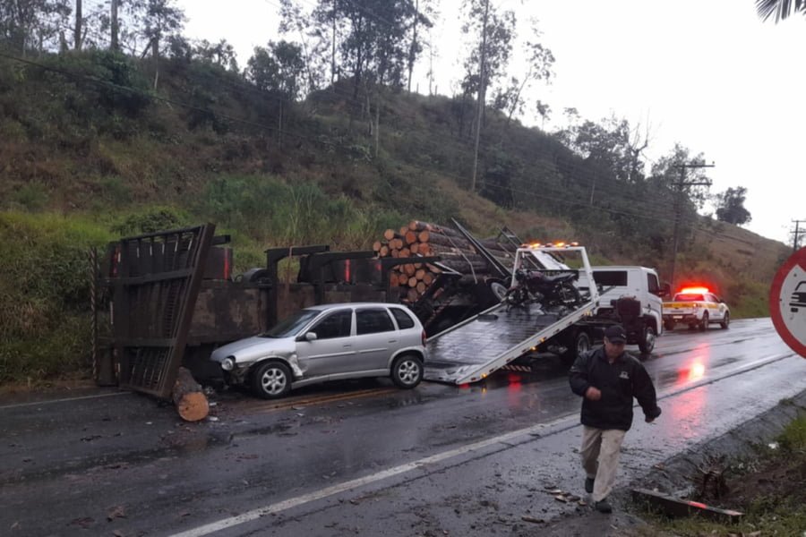 Caminhão carga de madeira tomba e carro bate em toras caídas na