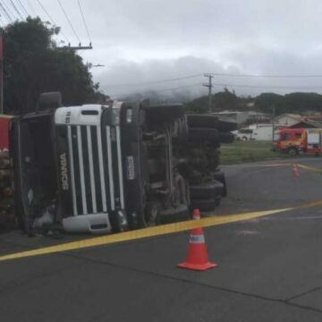 Motorista fica ferido após carreta carregada com toras de madeira tombar em Imbituba