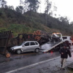 Caminhão com carga de madeira tomba e carro bate em toras caídas na pista (2)