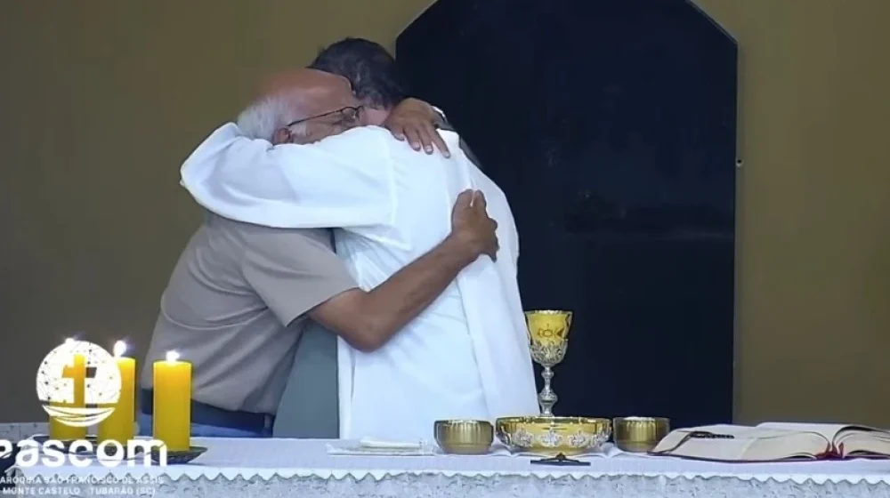 Avô que perdeu o neto abraça padre durante missa em Tubarão