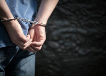 Arrested man in handcuffs with handcuffed hands behind back